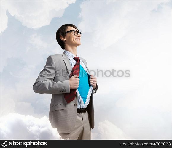 Determined super businessman . Young smiling businessman acting like super hero and tearing his shirt off