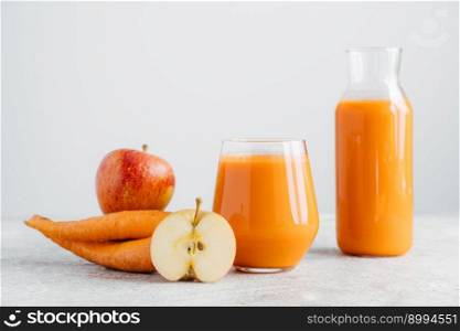 Detox drink in glass jar, slice of apple and carrot on white background. Refreshed homemade natural carrot beverage, ripe fruit and vegetable.