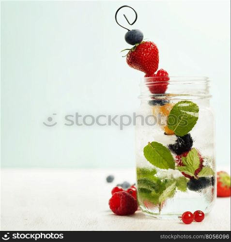 Detox fruit infused flavored water. Refreshing summer homemade cocktail. Fresh summer fruits on metal stick.