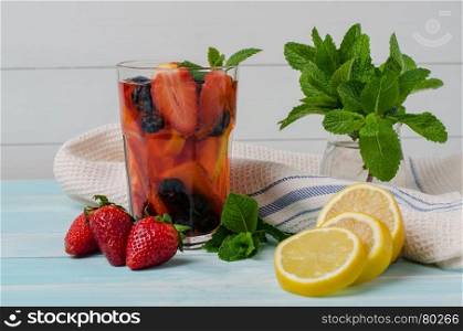 Detox fruit infused flavored water. Refreshing summer homemade cocktail with lemon, orange, strawberries and blueberries