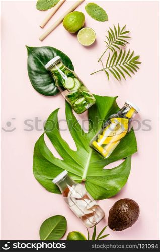 Detox fruit infused water, tropical fruits and leaves on pink pastel background. Detox fruit infused water. Detox fruit infused water