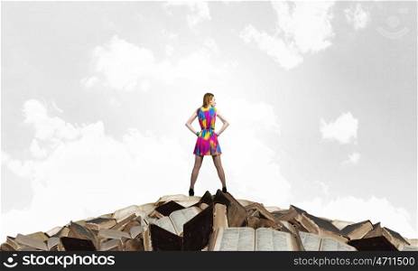 Develop your imagination. Woman in multicolored dress standing on pile of books