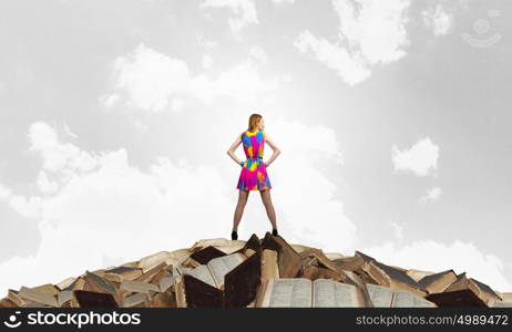 Develop your imagination. Woman in multicolored dress standing on pile of books