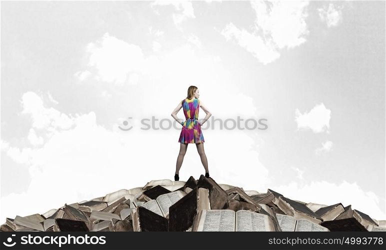 Develop your imagination. Woman in multicolored dress standing on pile of books