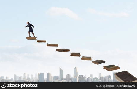 Develope your education level. Determined businesswoman climbing up ladder of books