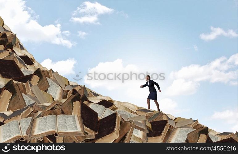 Develope your education level. Determined businesswoman climbing up pile of books