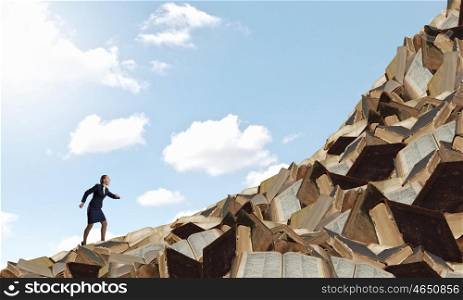 Develope your education level. Determined businesswoman climbing up pile of books