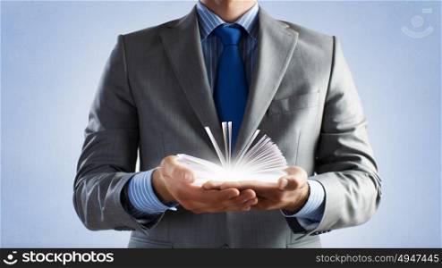 Develope your imagination. Close up of man holding opened book with flying out characters