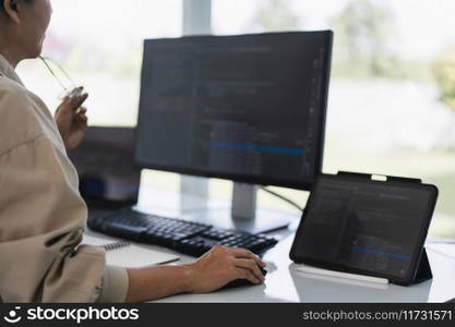 Developer programmer working to checking code on monitor while programming to developing website.