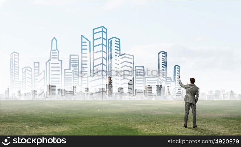 Development project. Back view of businessman drawing sketches of construction project on wall