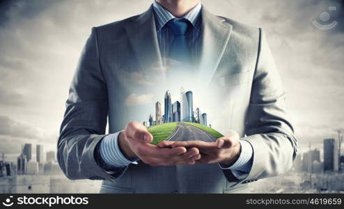 Development project. Close up of businessman holding city model in hands