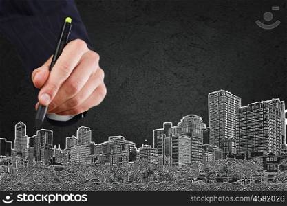 Development project. Close up of hand drawing urban buildings with marker