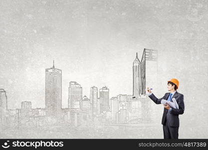 Development project. Young man engineer in helmet drawing construction project