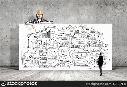 Development project. Young woman builder wearing helmet and holding banner with business sketches