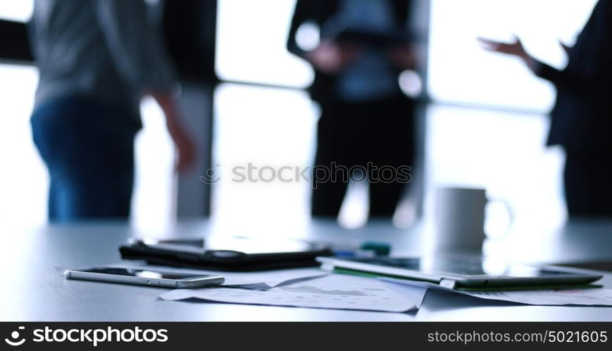 Devices on table with business people in background in modern office building