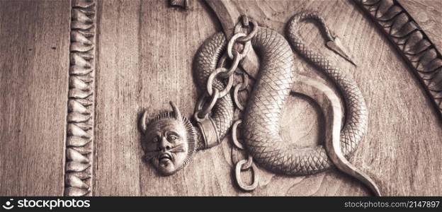Devil snake symbol. Fantasy magic creature on an old door, 12th Century Abbey, Italy.
