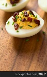 Deviled egg with bacon and chives, photographed with natural light (Selective Focus, Focus on the front of the egg yolk)