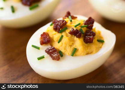 Deviled egg with bacon and chives, photographed with natural light (Selective Focus, Focus on the front of the egg yolk)