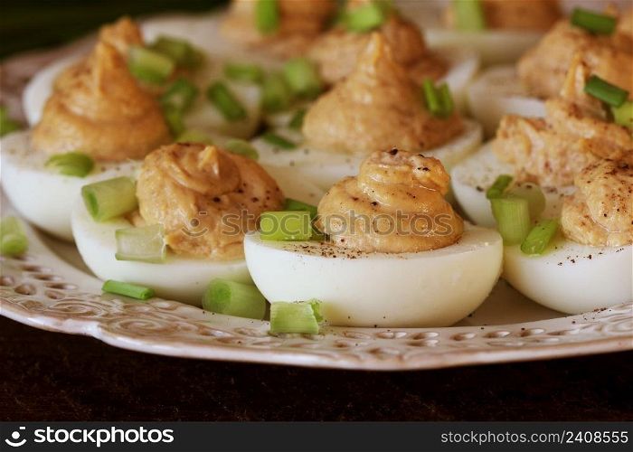 Deviled eggs with cod livers with leek on white plate. Rustic wooden table .. Deviled eggs with cod livers with leek on white plate. Rustic wooden table