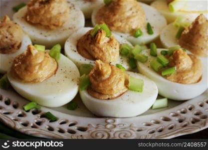 Deviled eggs with cod livers with leek on white plate. Rustic wooden table .. Deviled eggs with cod livers with leek on white plate. Rustic wooden table
