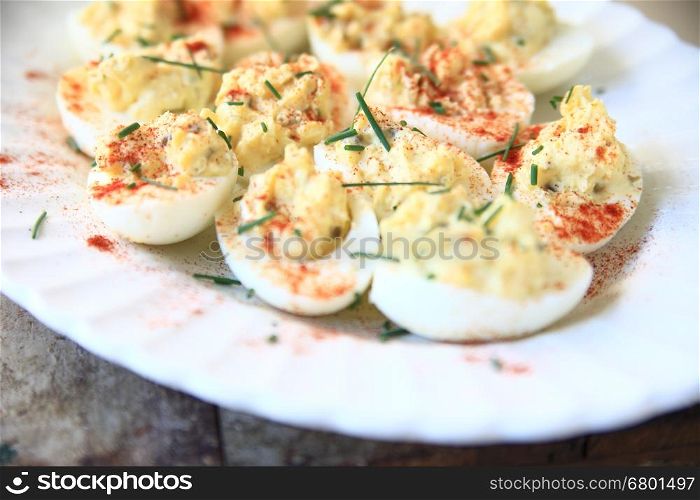 Deviled eggs with smoked paprika and chives on a white fluted platter
