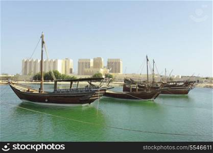 Dhows moored off Museum Park in central Doha, Qatar, Arabia, with some of the buildings from the city&rsquo;s commercial port in the background.