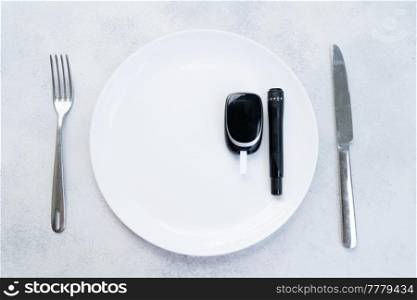 Diabetes diet planning concept, empty plate with fork, knife and glukemetr, fasting diet and dieabetes sugar level control equipment. Diabetes diet planning concept