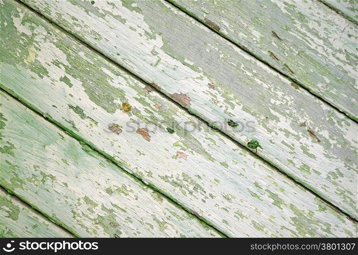 Diagonal boards with light green paint peeling off as background