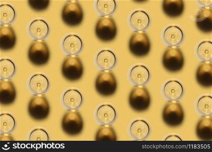 Diagonal pattern from glasses with white dry alcohol wine on a pastel yellow background with dark shadows. Top view.. Top view of alcohol white wine glasses pattern.