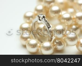 Diamond engagement ring in a channel setting and a pearl necklace