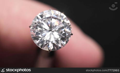Diamond gem in hand of gemologist or jeweller. Professional holding piece of jewelry, macro shot of a diamond in male hand.. Jeweller examines diamond