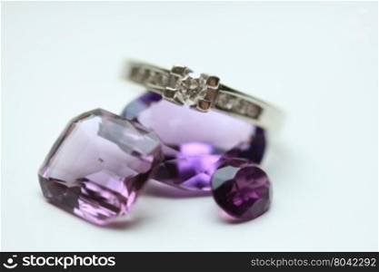Diamond ring on loose purple amethyst gemstones