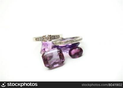 Diamond rings on loose purple amethyst gemstones