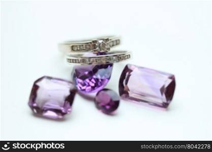 Diamond rings on loose purple amethyst gemstones