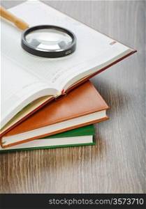 diaries and magnifier on wooden background