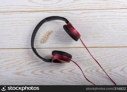 Dice-sized alphabet cubes spelling music and red headphones on wooden background