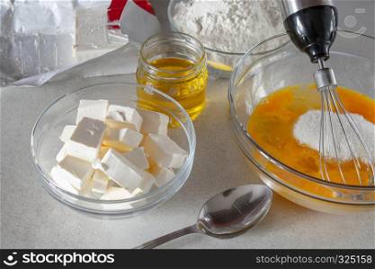 Diced butter in a bowl on the table. Eggs in a glass bowl with sugar.