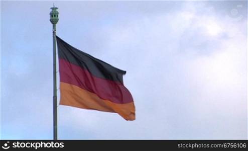 Die Flagge der Bundesrepublik Deutschland vor bedecktem Himmel.