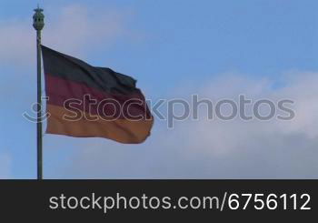 Die Flagge der Bundesrepublik Deutschland vor vor bew?lktem Himmel.