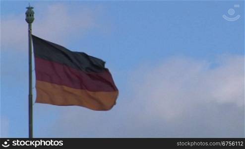 Die Flagge der Bundesrepublik Deutschland vor vor bew?lktem Himmel.