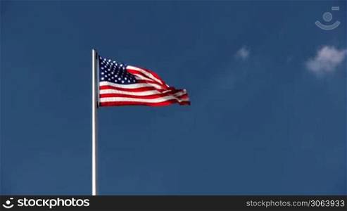 Die Flagge der USA weht im Wind vor blauem Himmel.