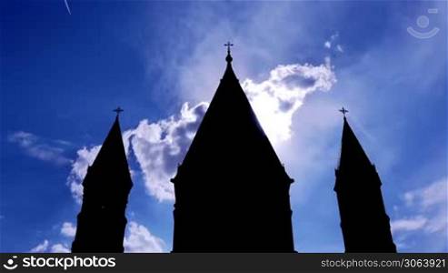 Die Turme einer Kirche sind zu sehen, Wolken ziehen schnell vorbei durch Zeitraffer. A church tower is shown, clouds move fastly, done by time lapse.