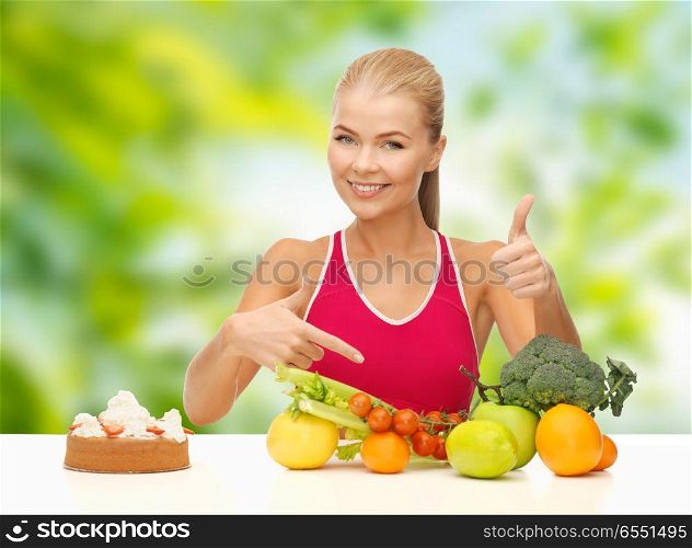 diet and eating concept - woman with vegetables and cake choosing healthy food over green natural background. woman choosing between vegetable food and cake. woman choosing between vegetable food and cake