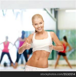diet and fitness concept - beautiful sporty woman showing thumbs up and her abs