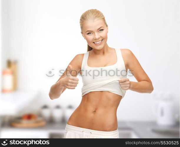 diet and fitness concept - beautiful sporty woman showing thumbs up and her abs