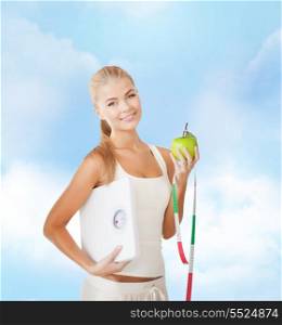 diet and fitness concept - beautiful sporty woman with scale, green apple and measuring tape