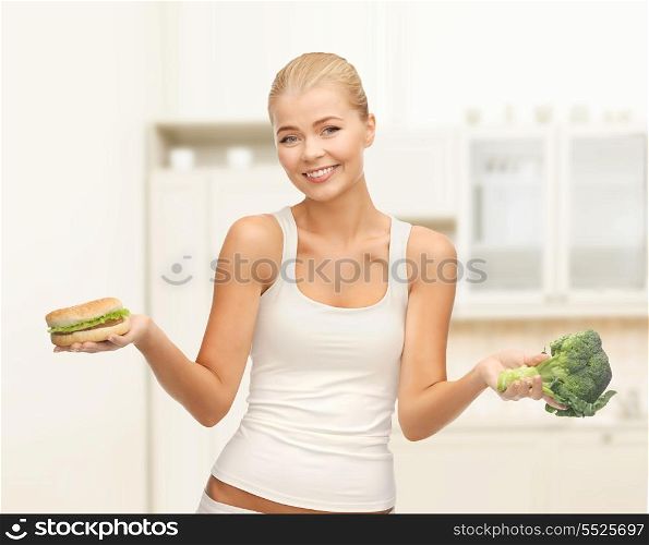 diet and fitness concept - sporty woman with broccoli and hamburger