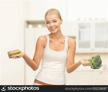 diet and fitness concept - sporty woman with broccoli and hamburger