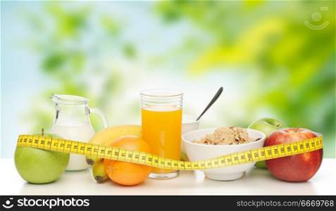 diet and healty eating concept - breakfast food and measuring tape on table over green natural background. breakfast food and measuring tape on table. breakfast food and measuring tape on table