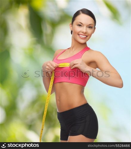 diet and sport concept - beautiful sporty woman measuring her breast